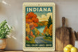 A vintage-style sign depicting a scenic autumn landscape with a road leading through it, surrounded by trees with orange and yellow foliage.