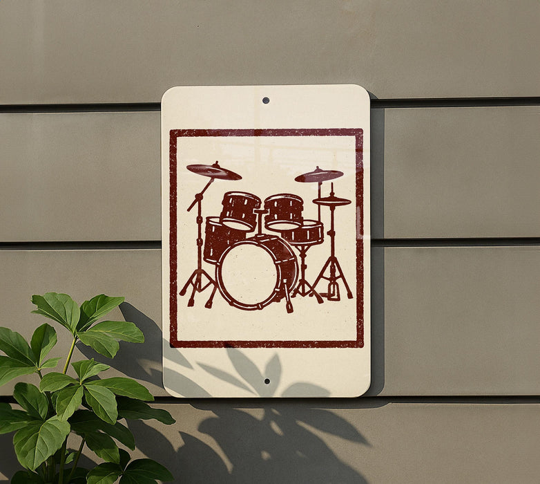 A sign with a drum set illustration is mounted on a wall, with a plant visible to the left.