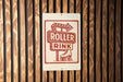 A sign for "Roller Rink" is displayed on a wooden wall.