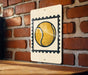 A sign featuring a tennis ball on a white background is mounted on a brick wall.