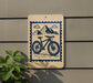 a sign with a bicycle and mountains in the background.