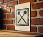 a sign with a symbol of a hammer and a nail on a brick wall.