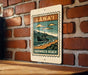 A sign for "SHIPWRACK BEACH" is hanging on a brick wall, featuring a vintage-style illustration of a ship on the beach.