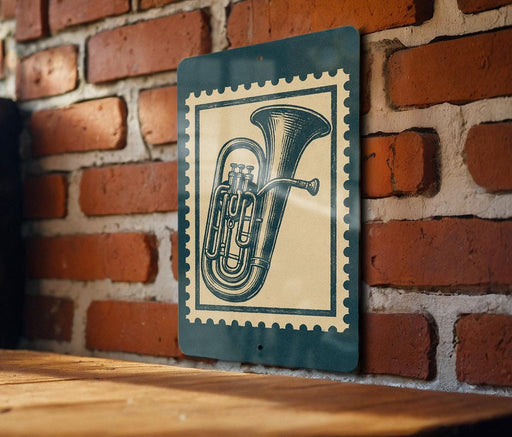 A metal sign with a vintage-style illustration of a tuba is mounted on a brick wall.