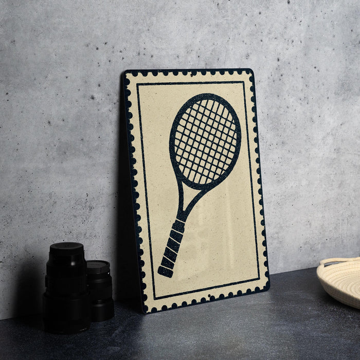 a framed tennis racket on a wall, with a stack of black camera lenses and a white plate or bowl placed next to it.