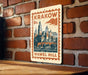 A metal sign with a vintage-style illustration of a castle or palace, mounted on a brick wall.