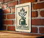 A sign with a graphic of a camp stove is mounted on a brick wall.