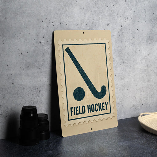 a sign for "field hockey" with a hockey stick symbol, placed on a table next to some black camera lenses.