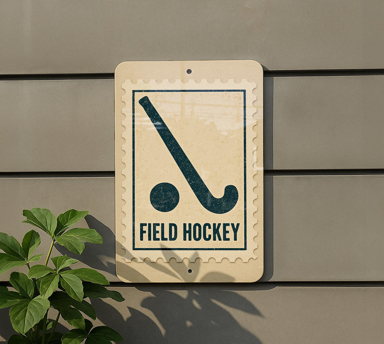 a sign that reads "FIELD HOCKEY" with a hockey stick symbol on it, mounted on a wall.