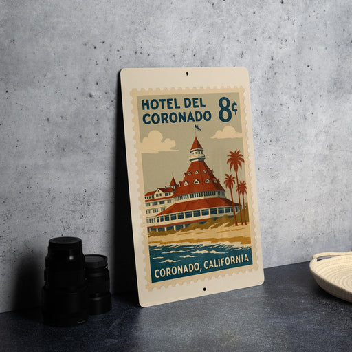 A vintage-style poster of the Hotel Coronado in California, featuring a large illustration of the hotel with palm trees and a beach in the background.