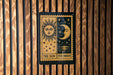 A sign with the sun and moon depicted on it, mounted on a wooden wall.