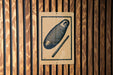 a sign with a black and white illustration of a fish and a stick, mounted on a wooden wall.