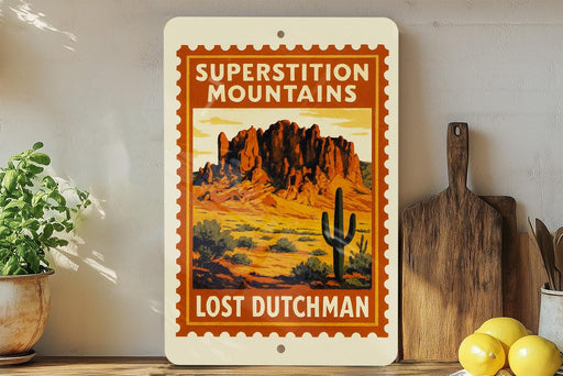 a vintage-style sign for "Superstition Mountains Lost Dutchman", with a desert landscape and a cactus on the sign. The sign is displayed on a shelf next to a wooden cutting board and a potted plant.