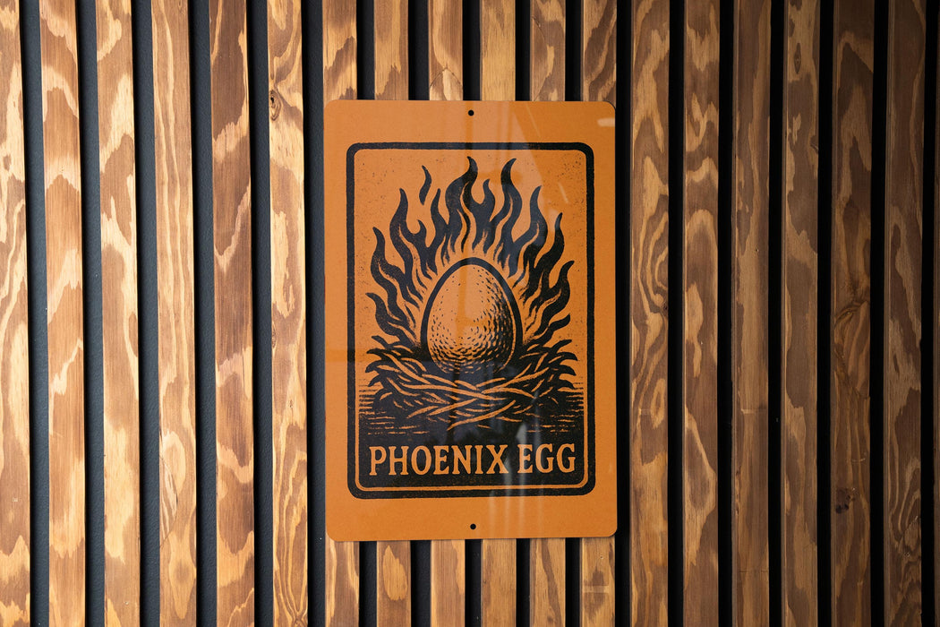 a sign with the text "PHOENIX EGG" and an illustration of a flaming egg nestled in a wreath.
