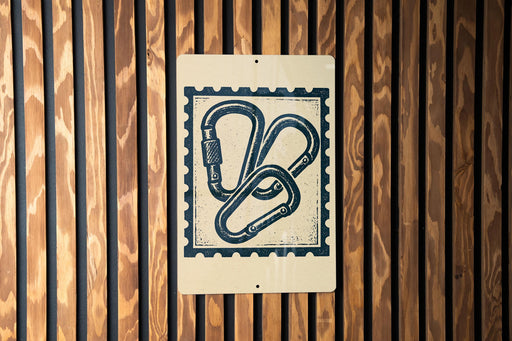 a sign with a graphic design of two climbing hooks mounted on a wooden wall.