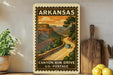 A vintage-style postage stamp from Arkansas depicting a scenic road leading to a canyon, with a car driving along the road.