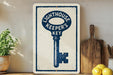 a sign with a key design, placed on a wooden surface next to a wooden cutting board and some lemons.
