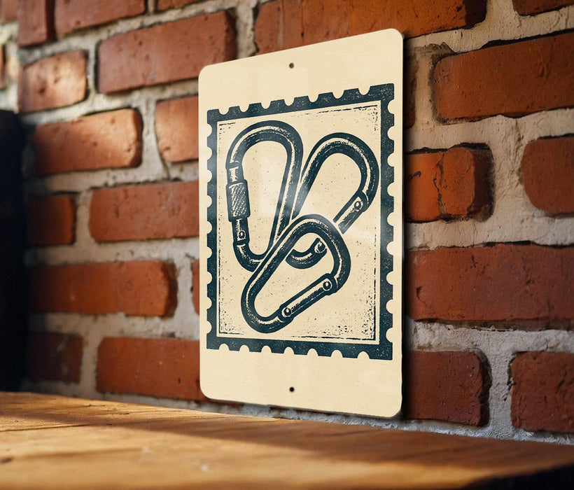 A sign with a graphic of two climbing ropes is mounted on a brick wall.