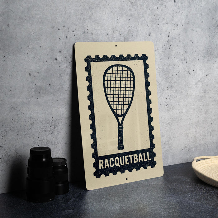 a racquetball sign with a racquet and the word "RACQUETBALL" printed on it, placed on a table next to some black camera lenses.