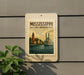 A sign for Mississippi Historic Waterfronts, featuring a lighthouse and a steamboat, is mounted on a gray wall.