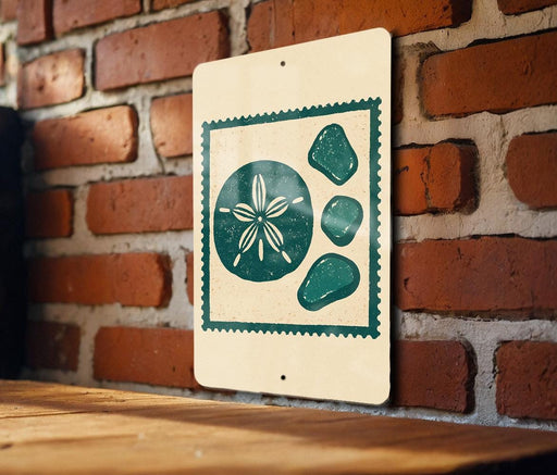 A sign with a seashell design is hanging on a brick wall.