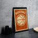 A vintage-style basketball-themed sign with the word "BASKETBALL" printed on it, standing on a gray countertop next to some black camera lenses.