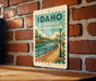 A vintage-style sign for Idaho Riverwalk promenade is displayed on a brick wall.