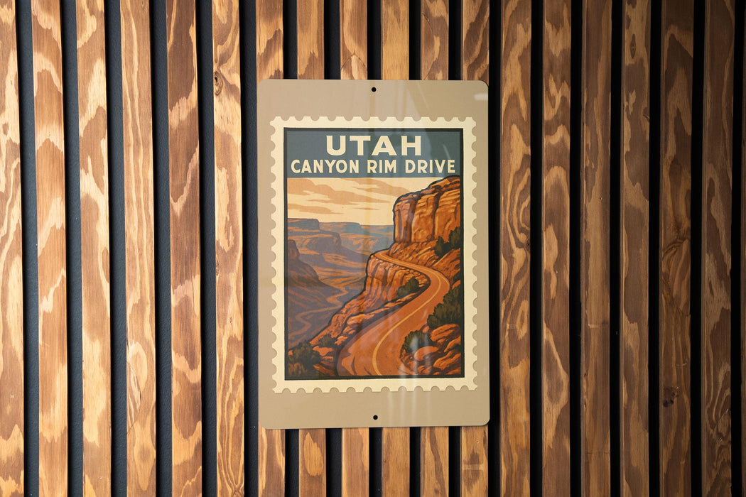 A vintage-style sign for Utah Canyon Rim Drive, featuring a scenic illustration of a winding road leading to a mountainous landscape.