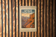 A vintage-style sign for Utah Canyon Rim Drive, featuring a scenic illustration of a winding road leading to a mountainous landscape.