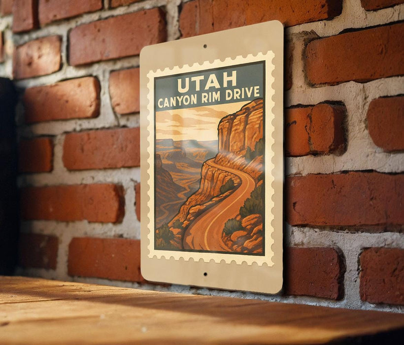 A framed poster of the scenic Utah Canyon Rim Drive, featuring a winding road and a mountainous landscape, is displayed on a brick wall.