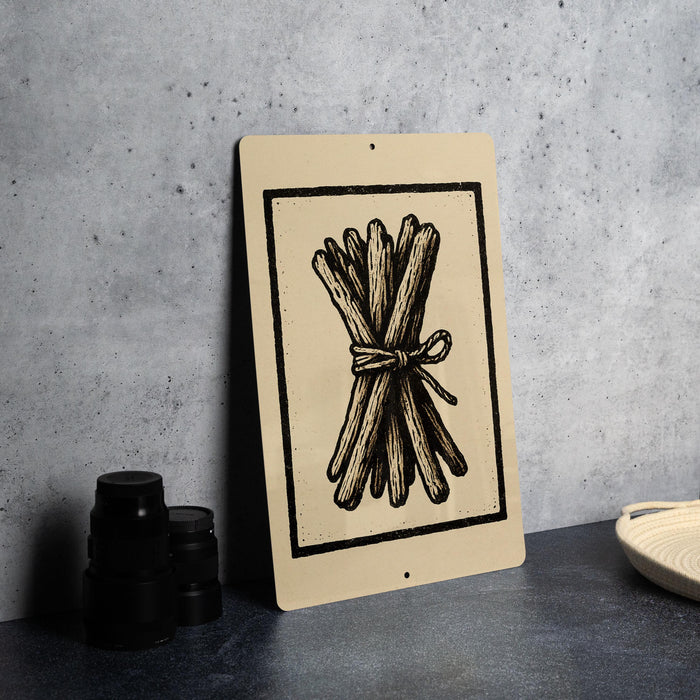 a beige sign with a black illustration of a bundle of sticks or branches, placed on a dark surface next to some black camera lenses.