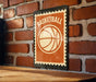 A vintage-style basketball-themed sign is displayed on a brick wall, featuring the word "BASKETBALL" prominently in the center.