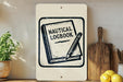 a nautical-themed sign with a book and pencil, placed on a wooden surface next to a wooden cutting board and some lemons.