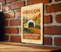 A vintage-style sign for the Covered Bridge Country in Oregon, featuring a wooden bridge and a scenic landscape.