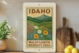 A vintage-style sign for the Idaho Wildflower Meadows Trail, featuring a scenic illustration of a meadow with wildflowers and a mountain backdrop.