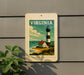 A vintage-style postage stamp depicting a lighthouse and coastal landscape, mounted on a wall.