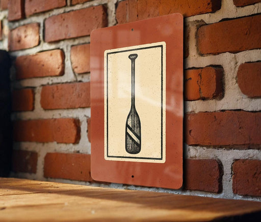 a sign with a paddle on it, mounted on a brick wall.
