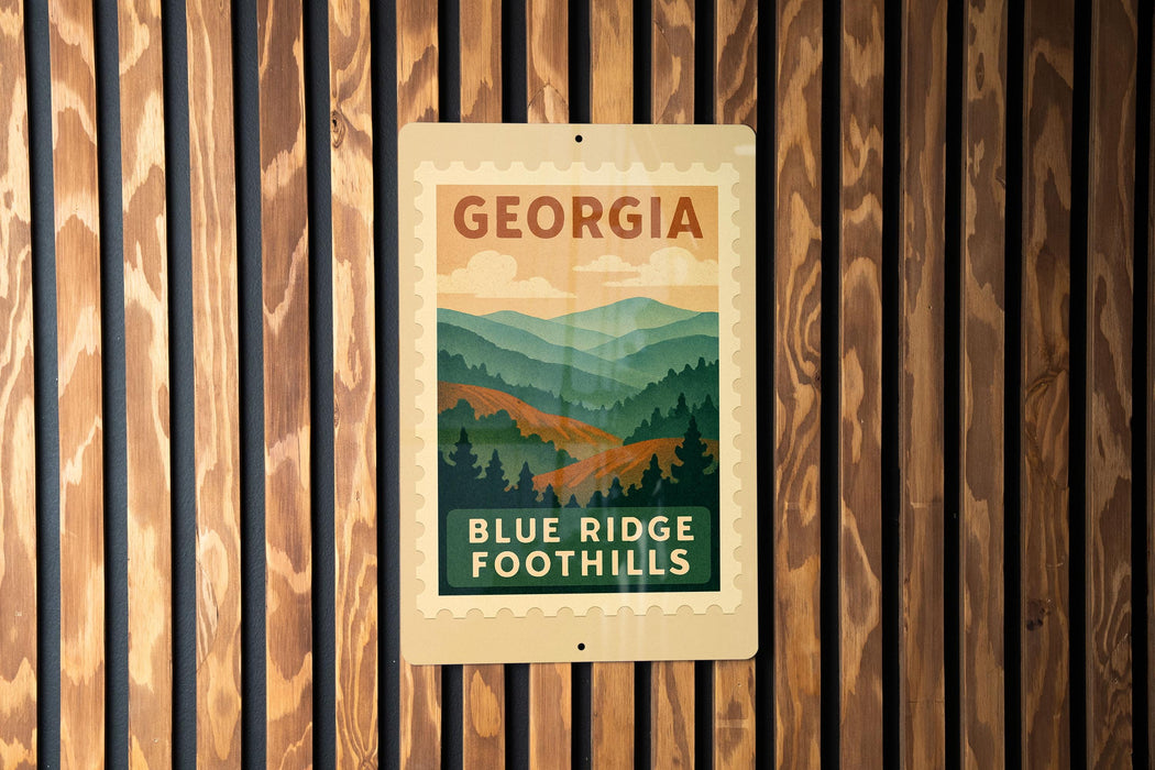 A sign for Blue Ridge Foothills in Georgia, featuring a mountain landscape with pine trees and a cloudy sky.