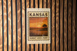 A Kansas sunset stamp sign is displayed on a wooden wall.
