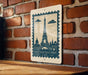 A framed image of the Eiffel Tower is displayed on a brick wall, with a wooden table below it.