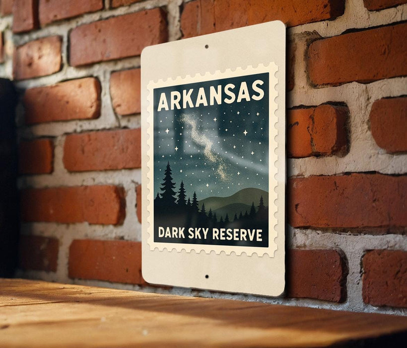 A sign for Arkansas' Dark Sky Reserve, featuring a night sky with stars and silhouetted trees, mounted on a brick wall.