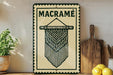 a decorative sign with a macrame design, placed on a wooden surface next to a wooden cutting board and some lemons.
