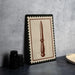 a framed picture of a knife with a brown border, placed on a countertop next to some black camera lenses.