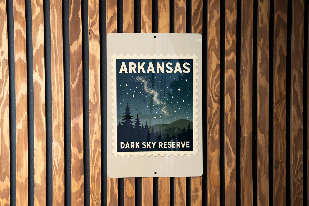 A sign for Arkansas Dark Sky Reserve, featuring a night sky with stars and silhouetted trees, mounted on a wooden wall.