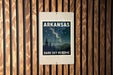 A sign for Arkansas Dark Sky Reserve, featuring a night sky with stars and silhouetted trees, mounted on a wooden wall.
