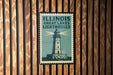 A vintage-style sign for the Illinois Great Lakes Lighthouses, featuring a lighthouse illustration on a wooden background.
