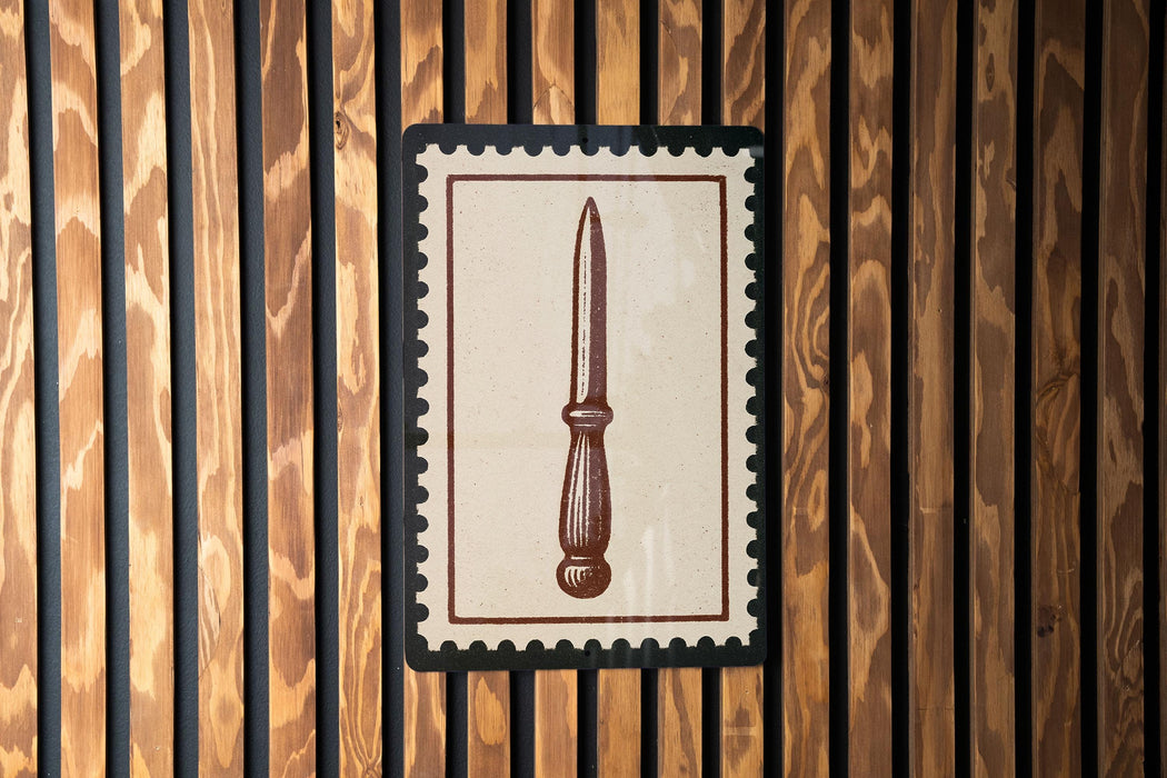 a wooden wall with a framed picture of a knife hanging on it.