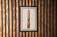 a wooden wall with a framed picture of a knife hanging on it.