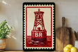 a framed print of a red buoy with the letter "B" on it, displayed on a shelf next to a wooden cutting board and some potted plants.