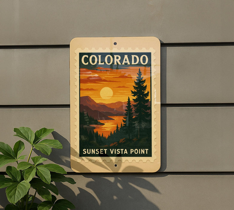A sign for the Sunset Vista Point in Colorado, featuring a scenic landscape with mountains, pine trees, and a sunset over the water.